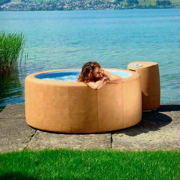 Evergreen softub hot tub set up outdoors by water with a woman enjoying soaking